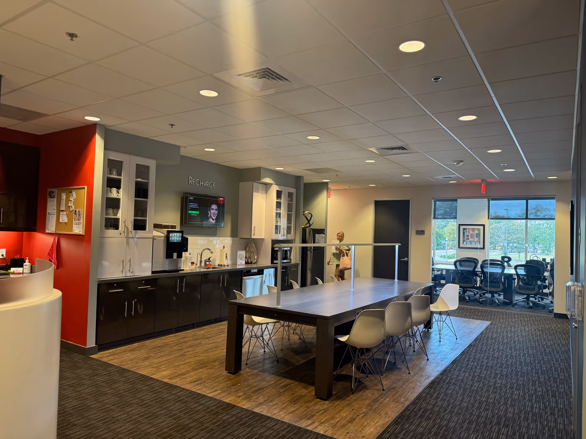 Interior of a senior living facility: a long communal table beside a kitchenette and seating.