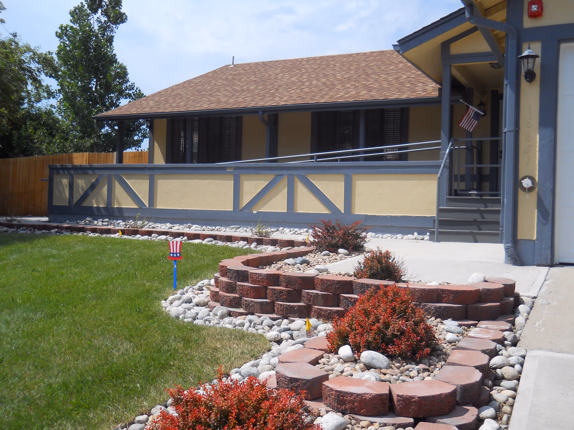 Front exterior of a Phoenix Senior Living building with a landscaped brick garden and stairs.