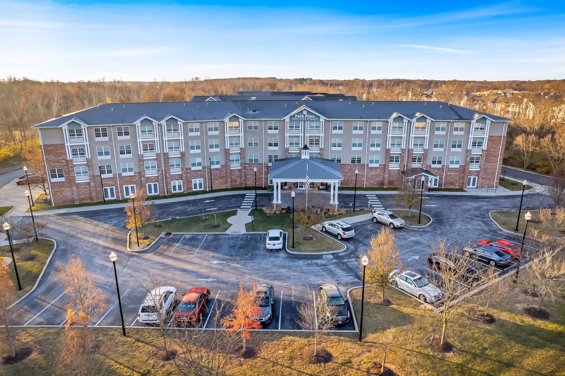 A multi-story Park Place at Winghaven senior living building with a circular driveway and parked cars.