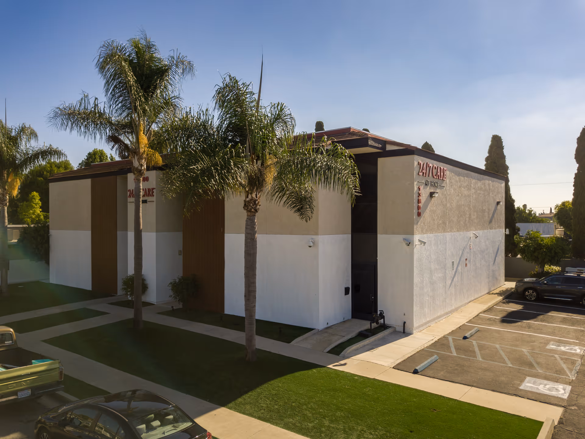 Exterior view of a senior care facility with palm trees and parking.
