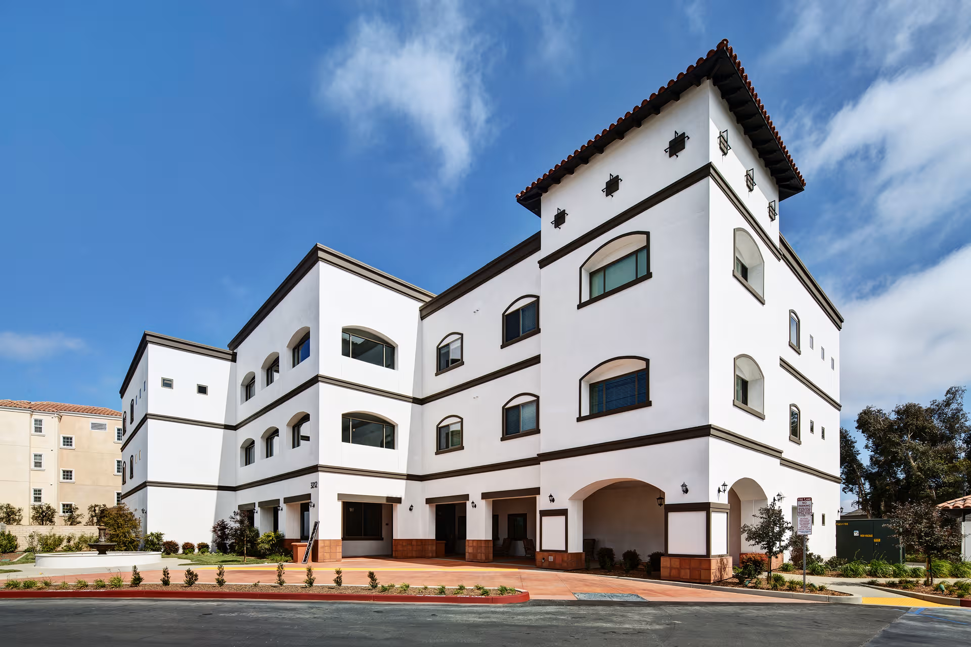 White multi-story senior living building, Clearwater at South Bay, with arches and a central tower.