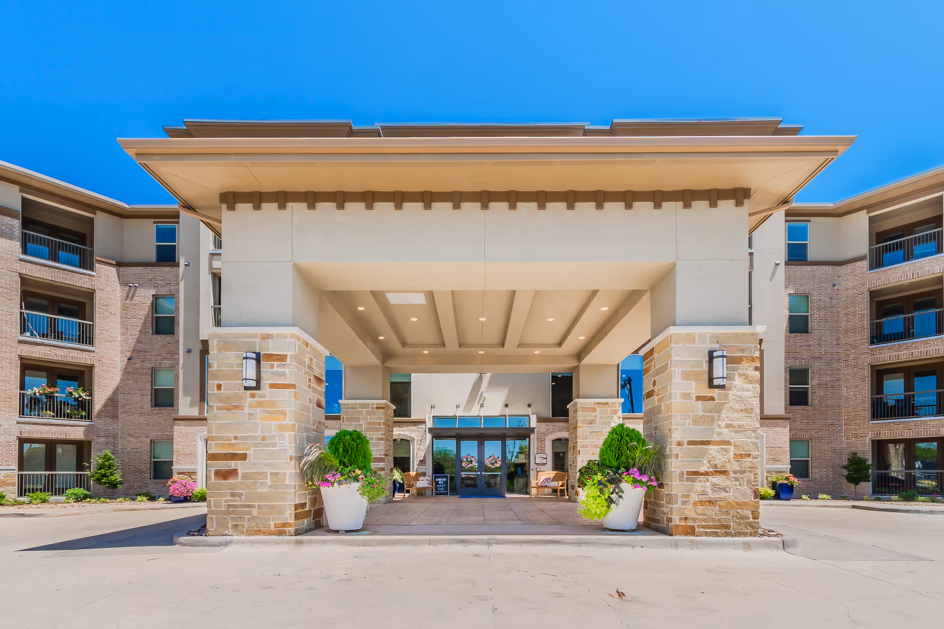 Front entrance of Atlas Point at Prestonwood with brick columns, stone accents, and planters.