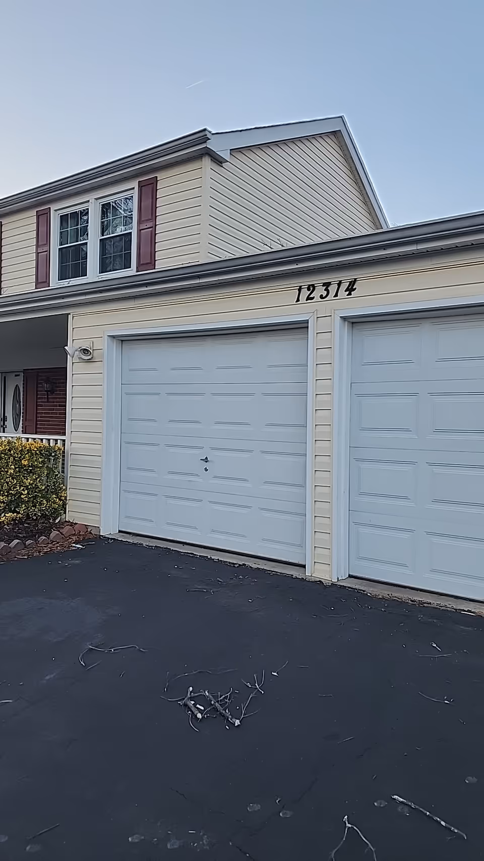 Beige senior living building front with two white garage doors and a driveway.