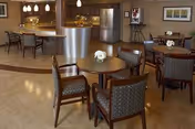 Interior dining and lounge area with round tables, chairs, and a curved bar.