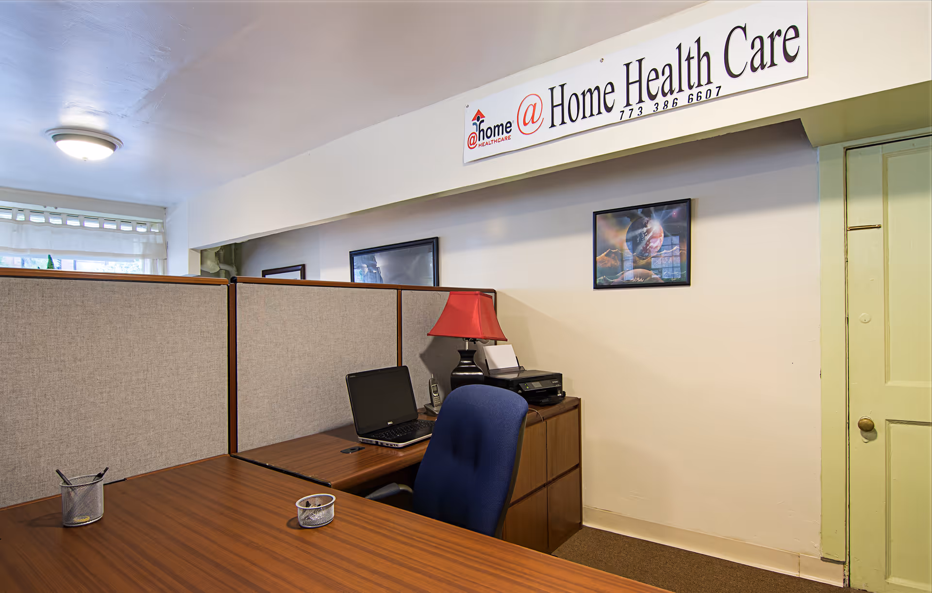 Interior office area with cubicles, desk, laptop, printer, and a Home Health Care sign.