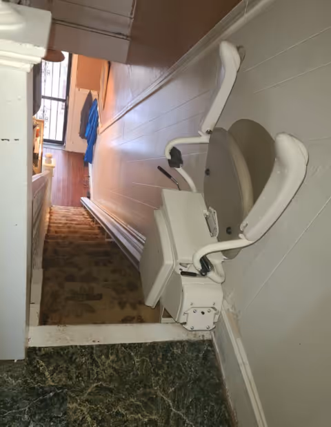 Indoor stairlift attached to a narrow staircase in a senior living facility.