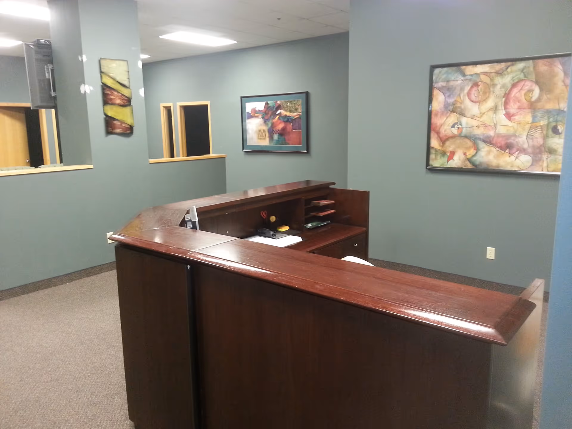 Curved wooden reception desk in a blue-walled interior with framed art.