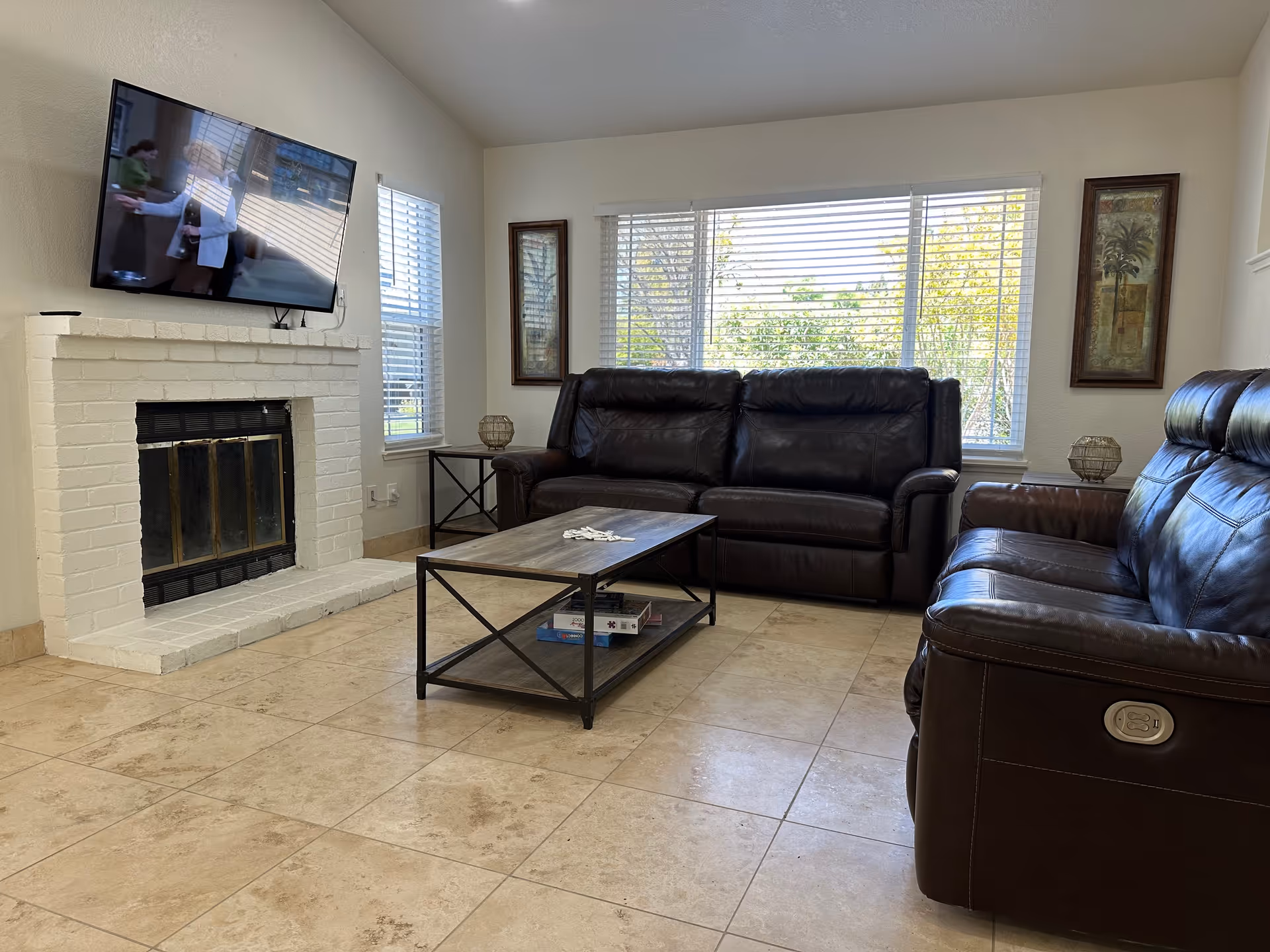 A cozy living room with leather sofas, a coffee table, and a wall-mounted TV.
