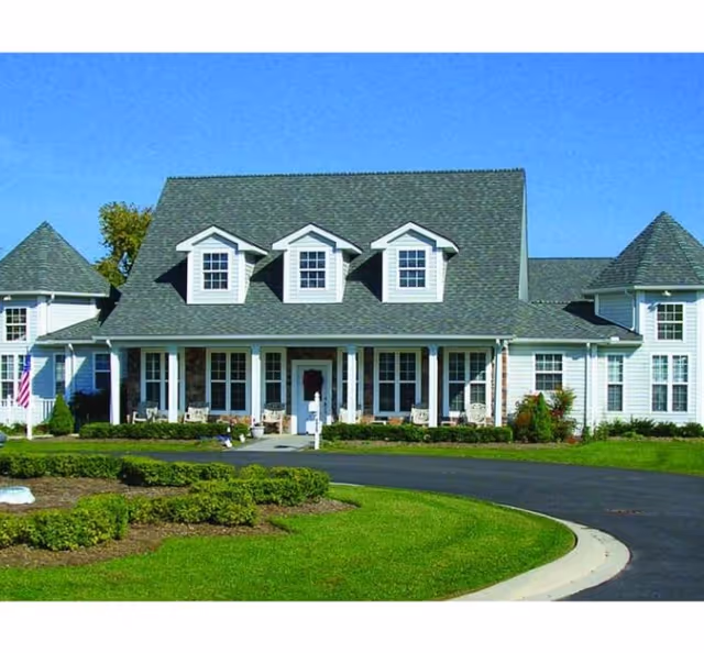 Front exterior of a senior living facility with a curved driveway and manicured lawn.