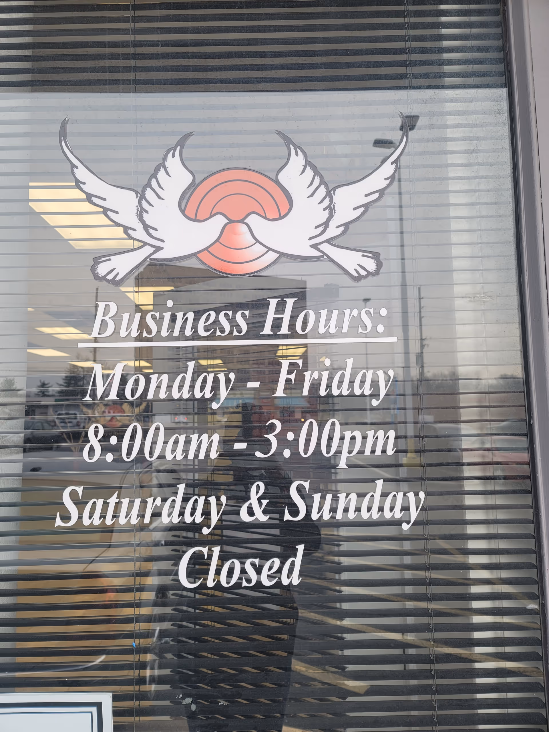 Glass window sign displays business hours and wings logo for the facility.