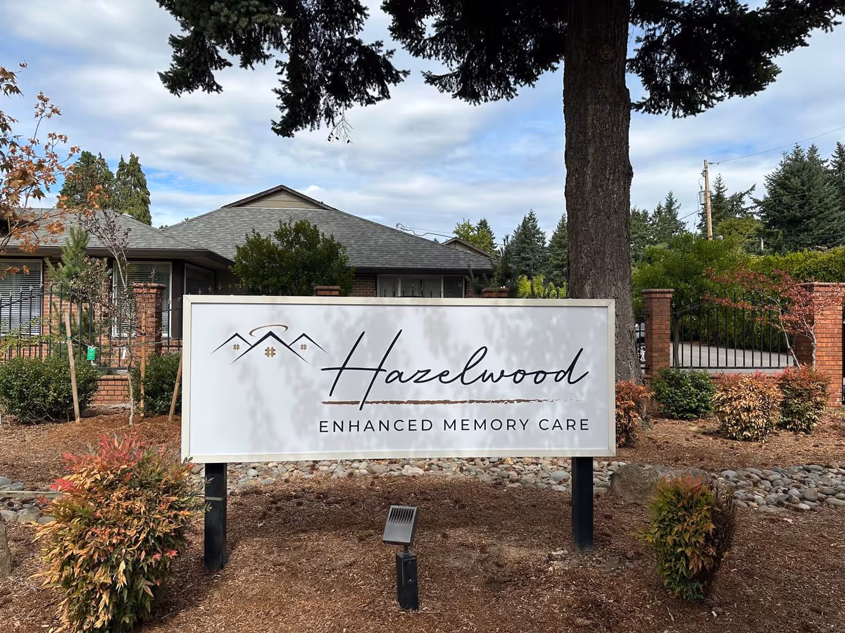 A large sign reading Hazelwood Enhanced Memory Care in a landscaped front yard.