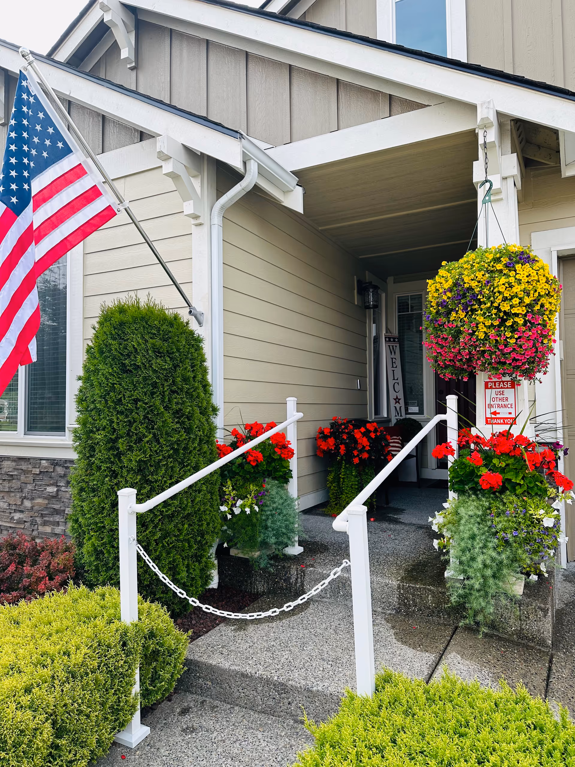 Front entrance of Home Life Care Adult Family Home with American flag and hanging flowers
