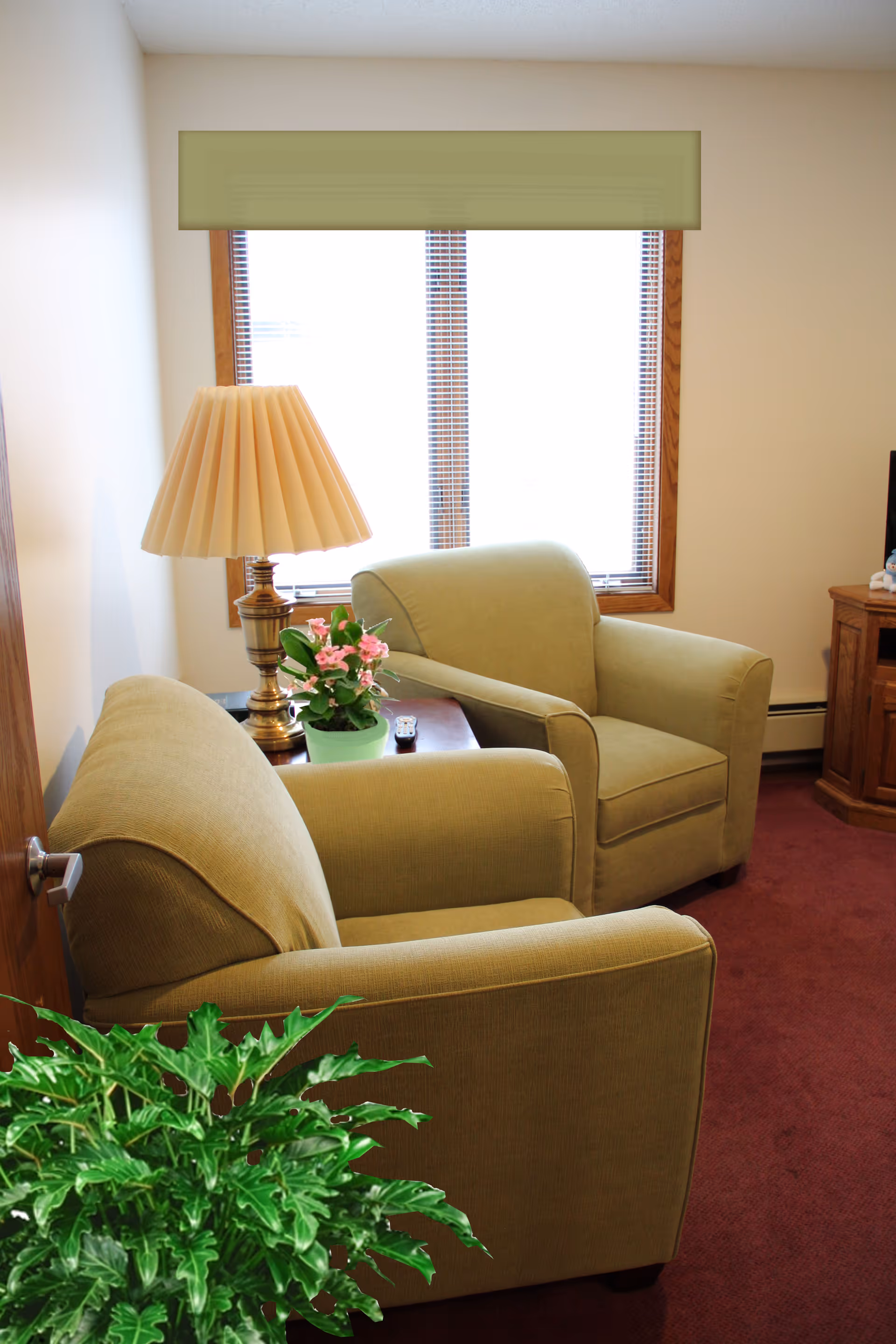 Two beige armchairs with a wooden table and lamp in a cozy living area.