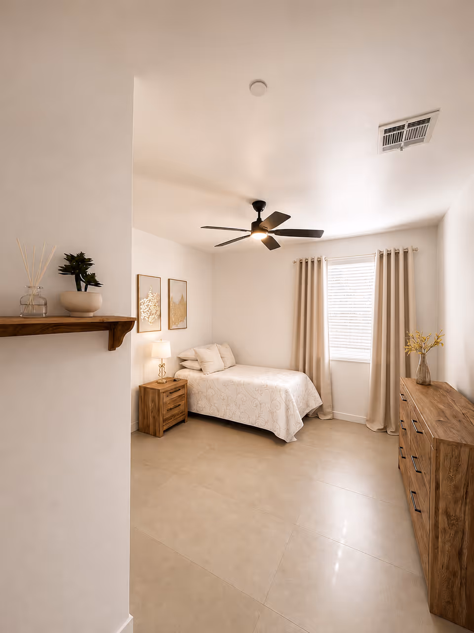 A cozy senior living bedroom with bed, dresser, nightstand, curtains, and ceiling fan.
