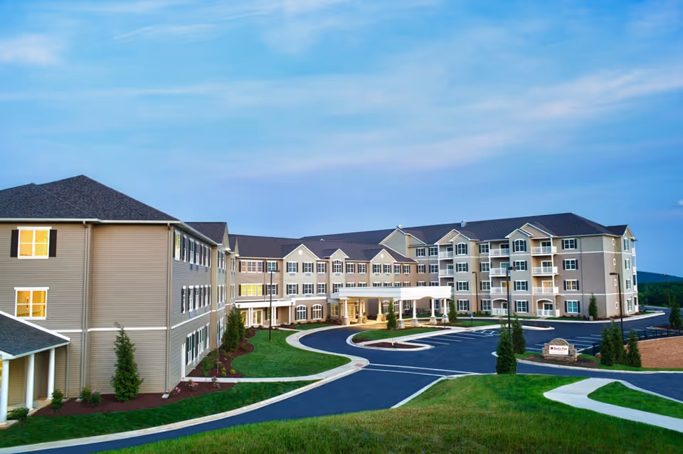Exterior view of a senior living facility with a circular driveway and landscaped grounds.