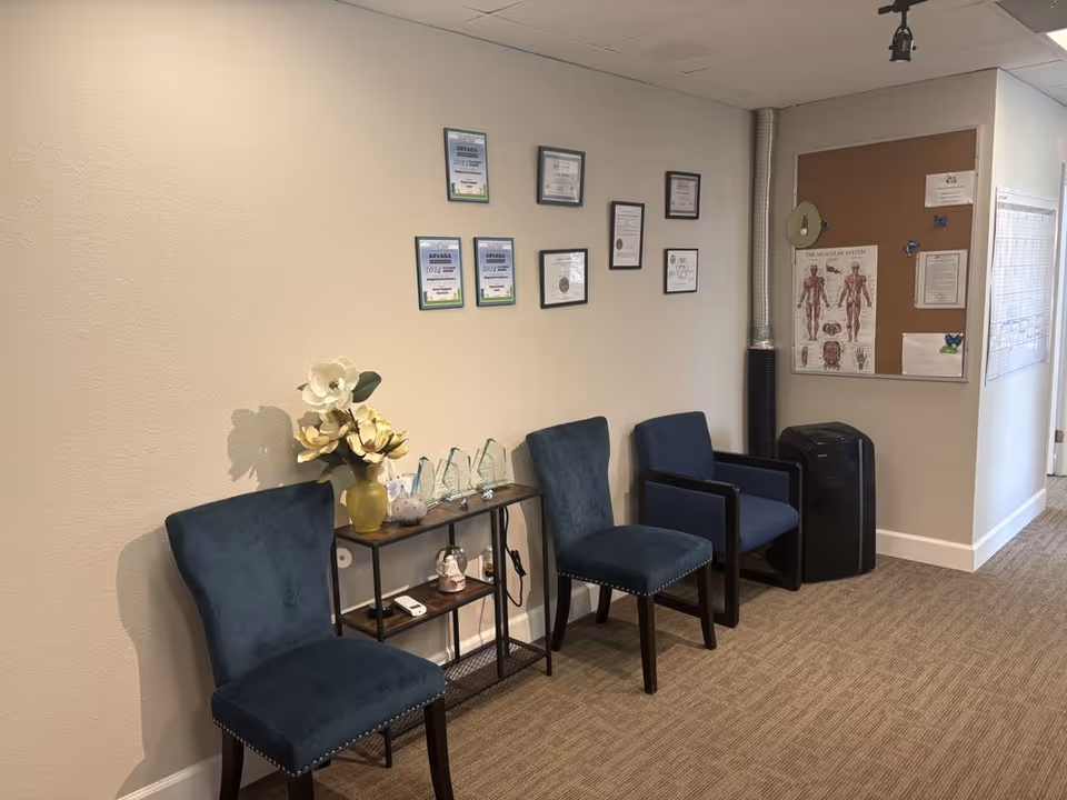 A small interior waiting area with blue chairs, wall plaques, and a corkboard.