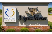 Exterior sign for Pilgrim Manor with crest and Senior Care Centers logo