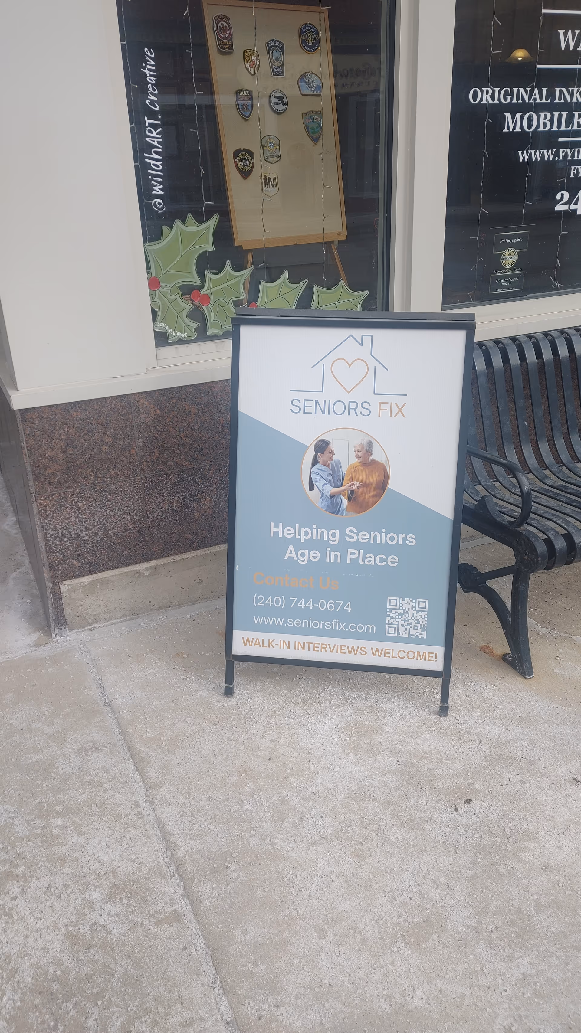 Sidewalk view with a bench beside a Seniors Fix sign outside storefront.