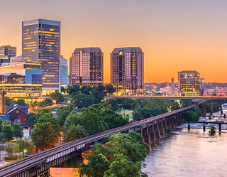 Sunset over Richmond skyline with river, trees, and a bridge spanning the water.