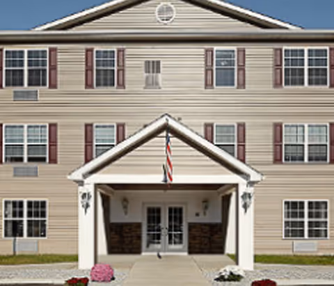 Front exterior view of Harborcreek Senior Apartments building with entryway and flag.