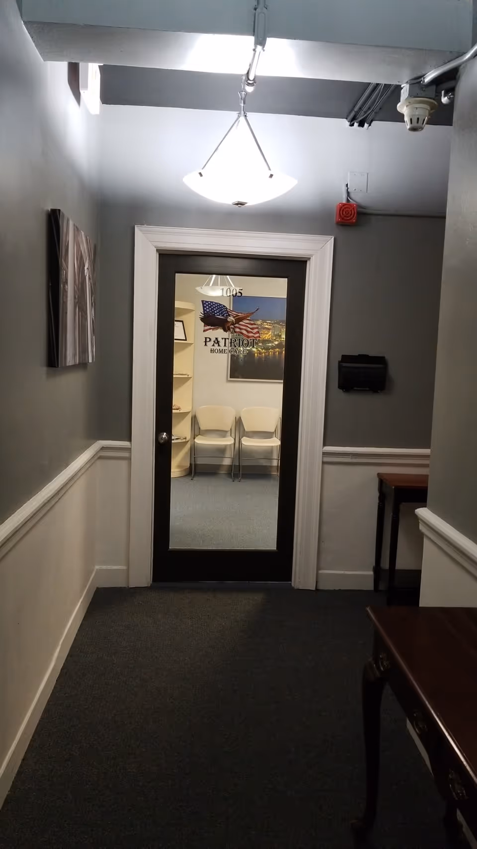 Hallway leading to a small meeting room with two white chairs and a patriotic poster