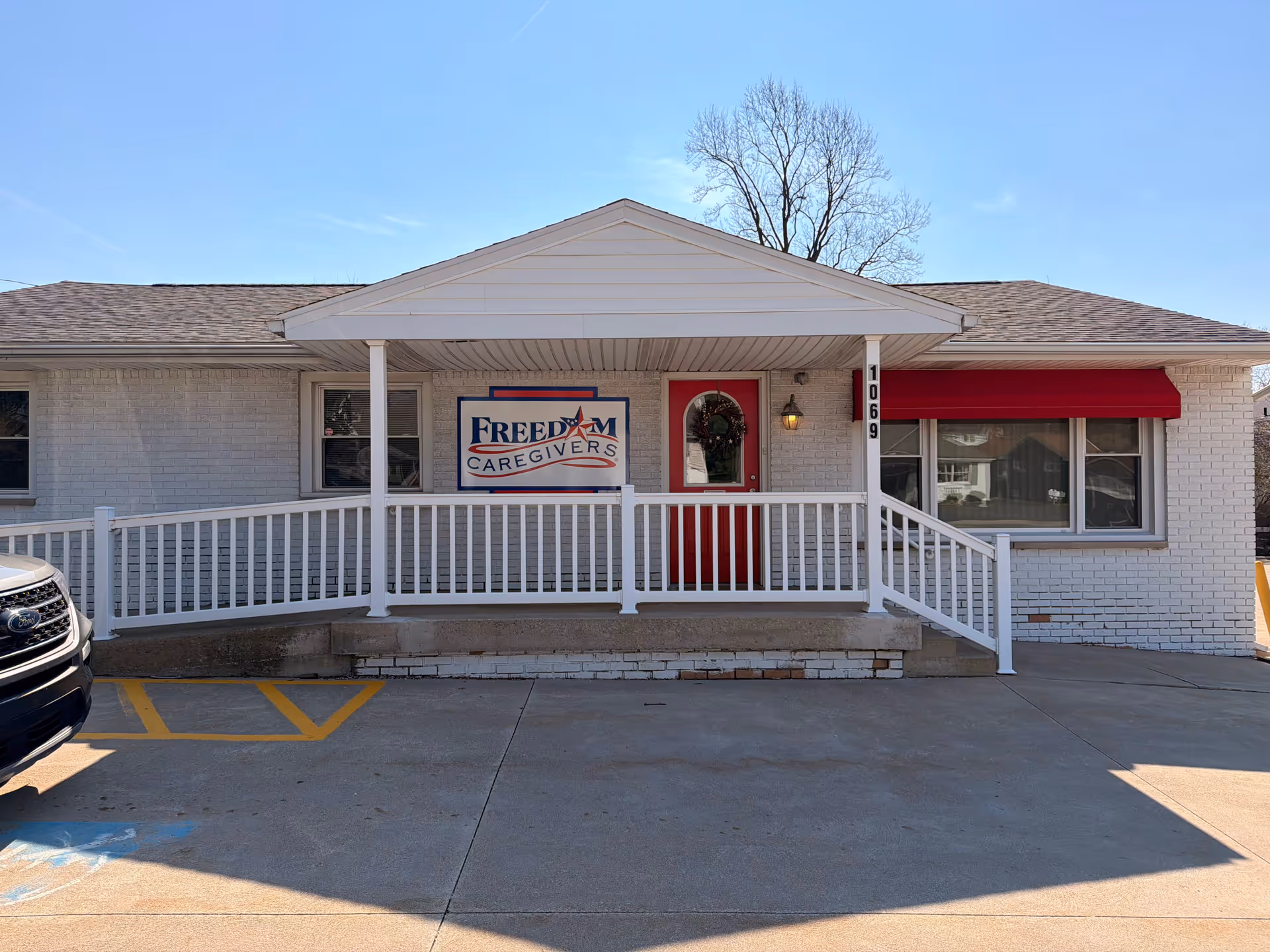 Front view of Freedom Caregivers Mansfield building with white brick, red door, and sign.