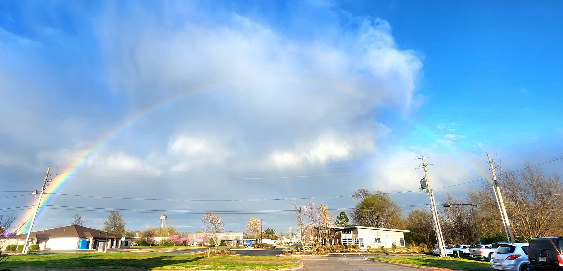 Exterior view of Visiting Angels Senior Home Care Fort Smith facility with rainbow across cloudy sky.