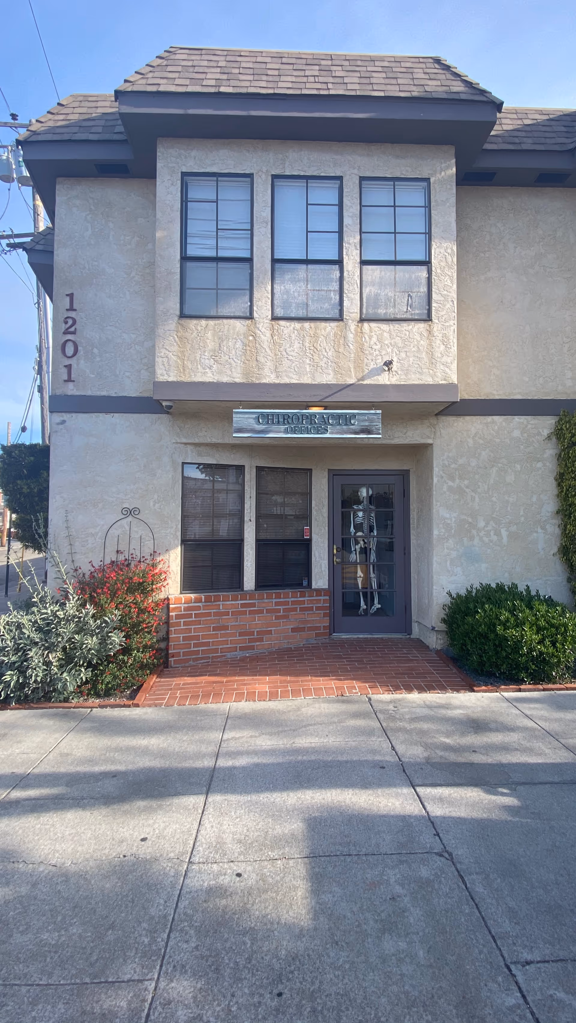 Chiropractic services sign above entrance to beige two-story building.