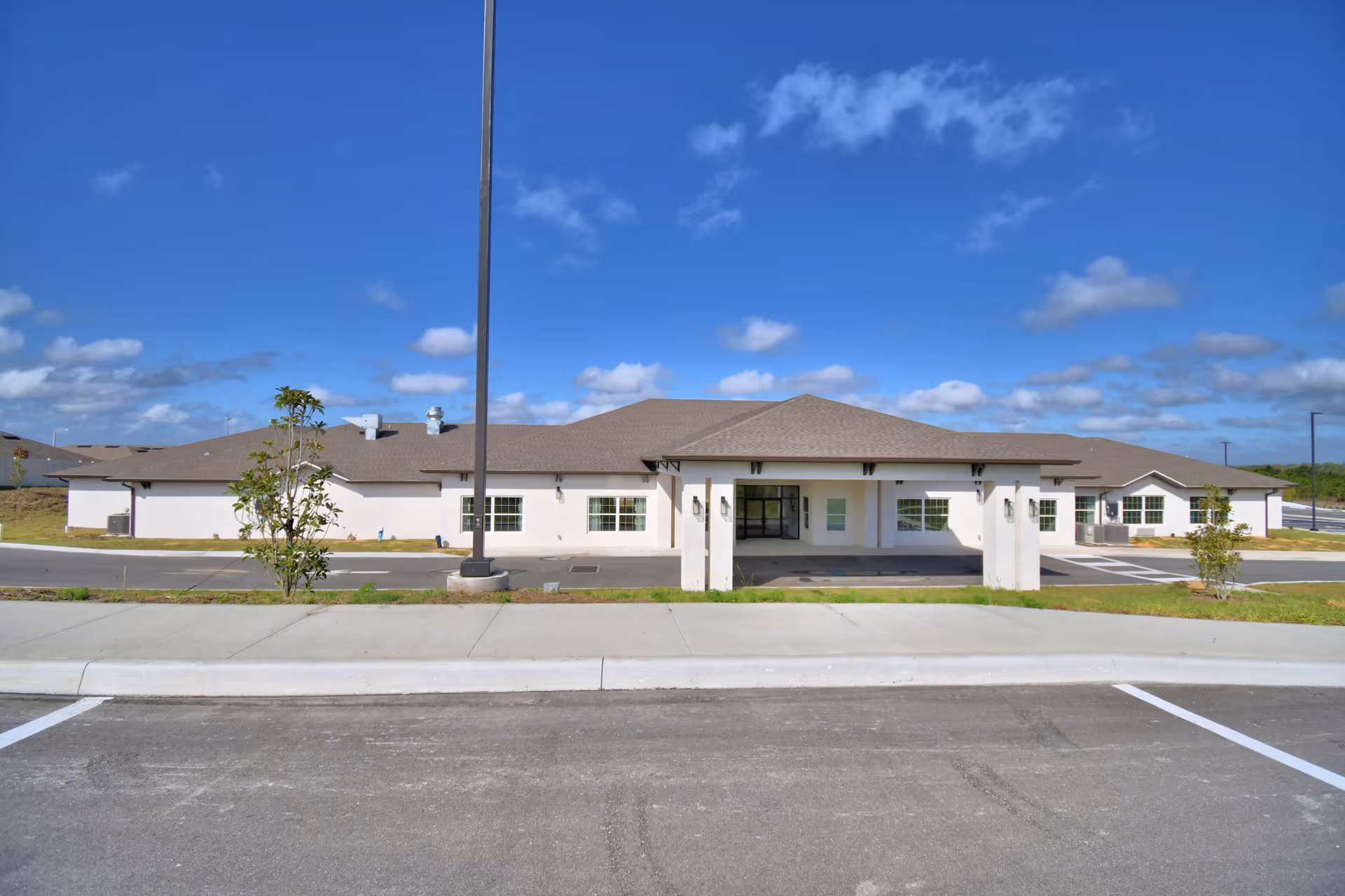 Single-story senior living facility exterior with entrance canopy and parking area.