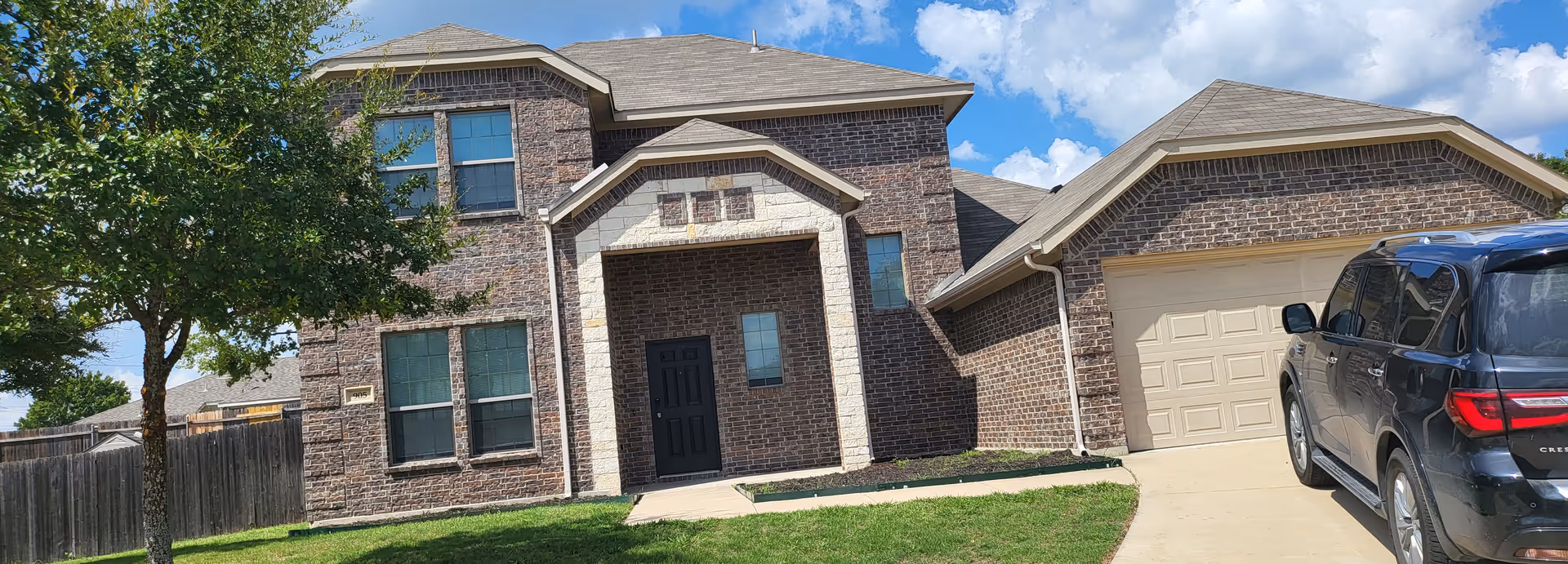 Brick senior living facility front exterior with driveway, garage, and a parked SUV.