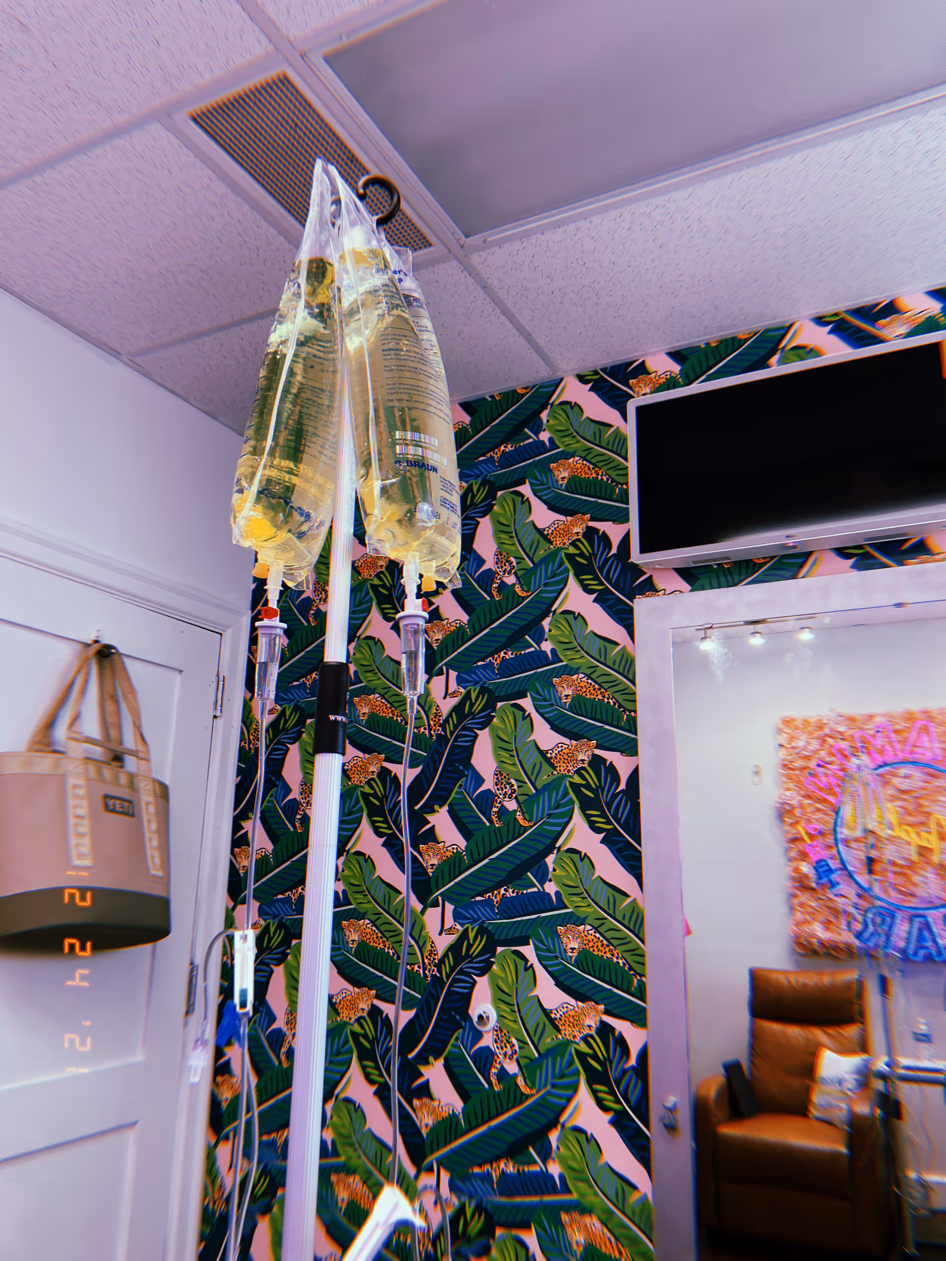 IV bags hang from stands in a tropical-themed treatment room.