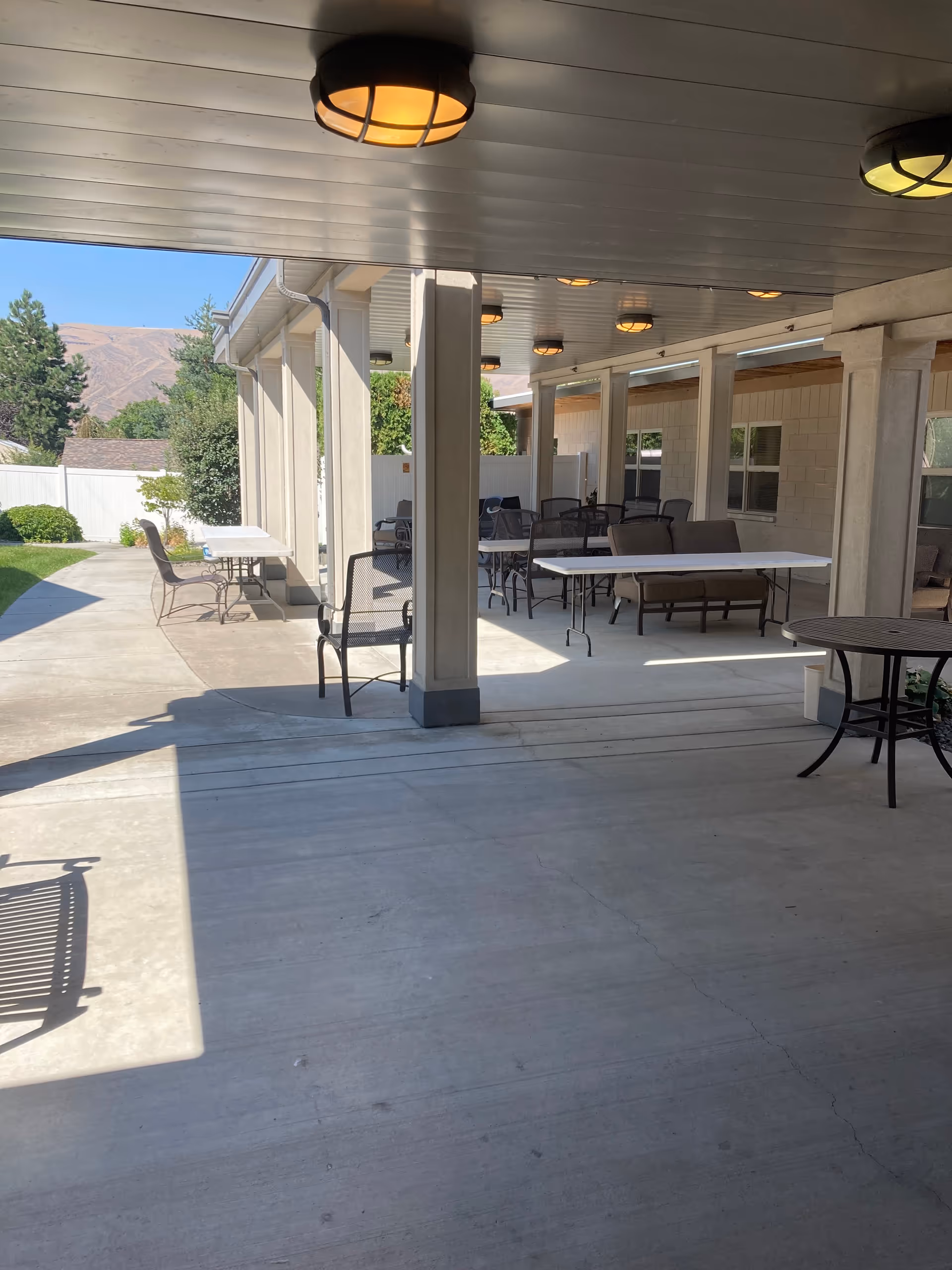 Covered outdoor patio with tables and chairs at a care facility.