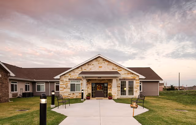 Oxford Glen at Owasso exterior building entrance with stone facade, walkway and benches.