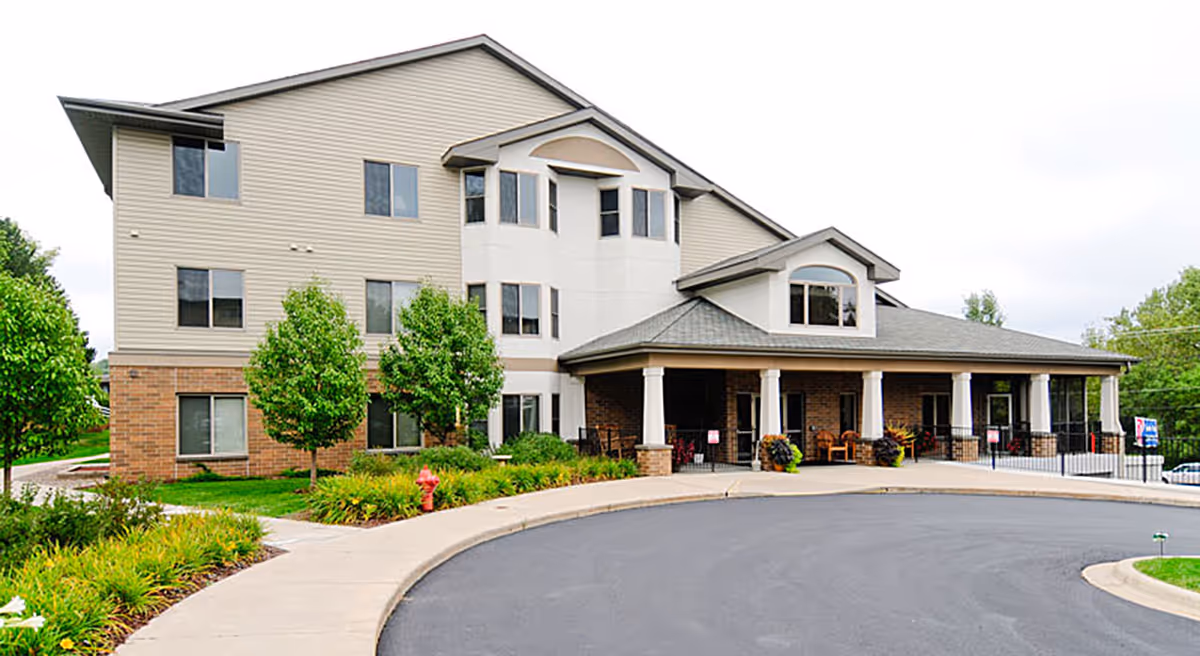 Exterior view of a multi-story senior living facility with a covered entrance and landscaping.