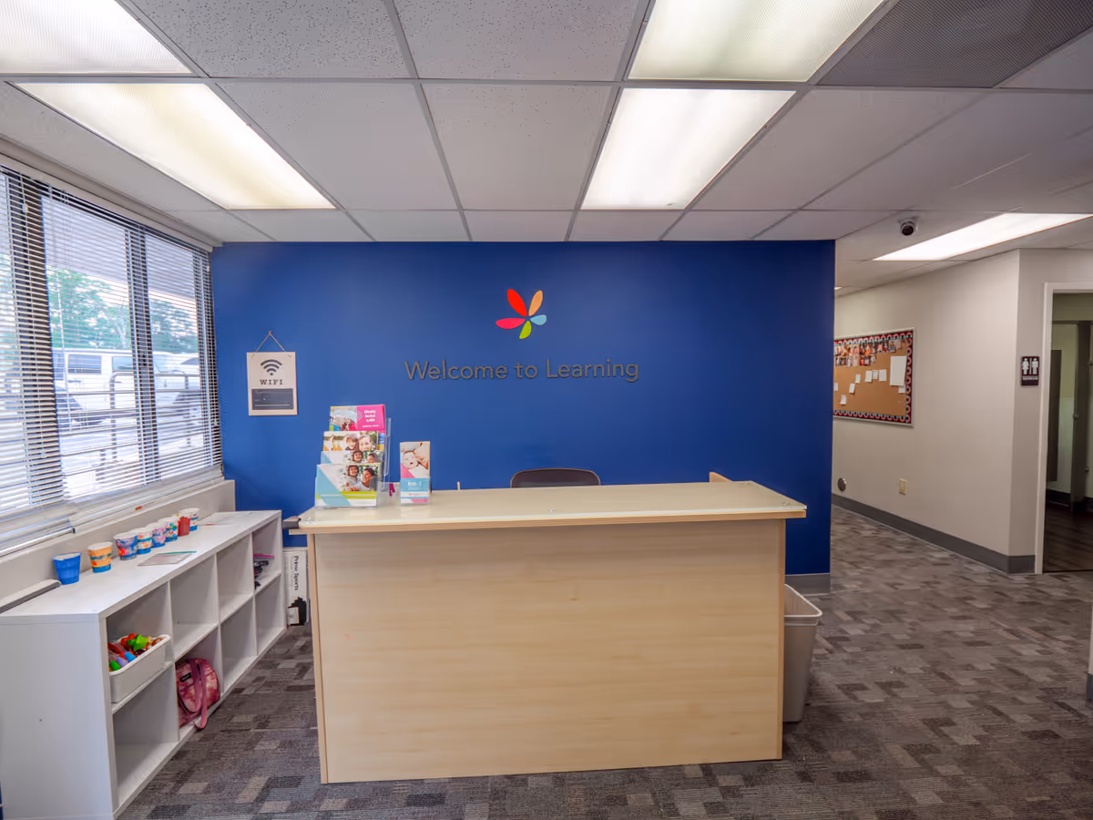 Front desk in a blue-walled learning center with a 'Welcome to Learning' sign.