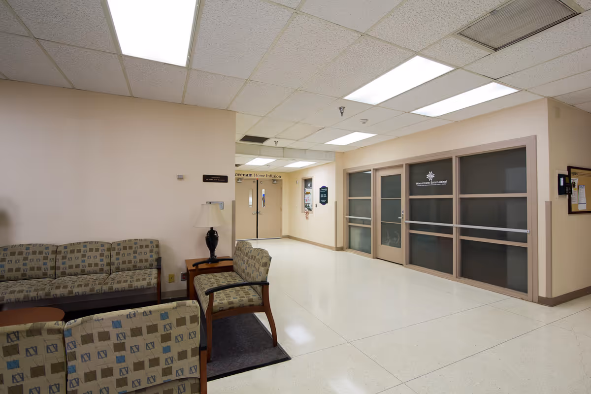 Lobby seating area with beige walls and glass doors in a senior care facility.