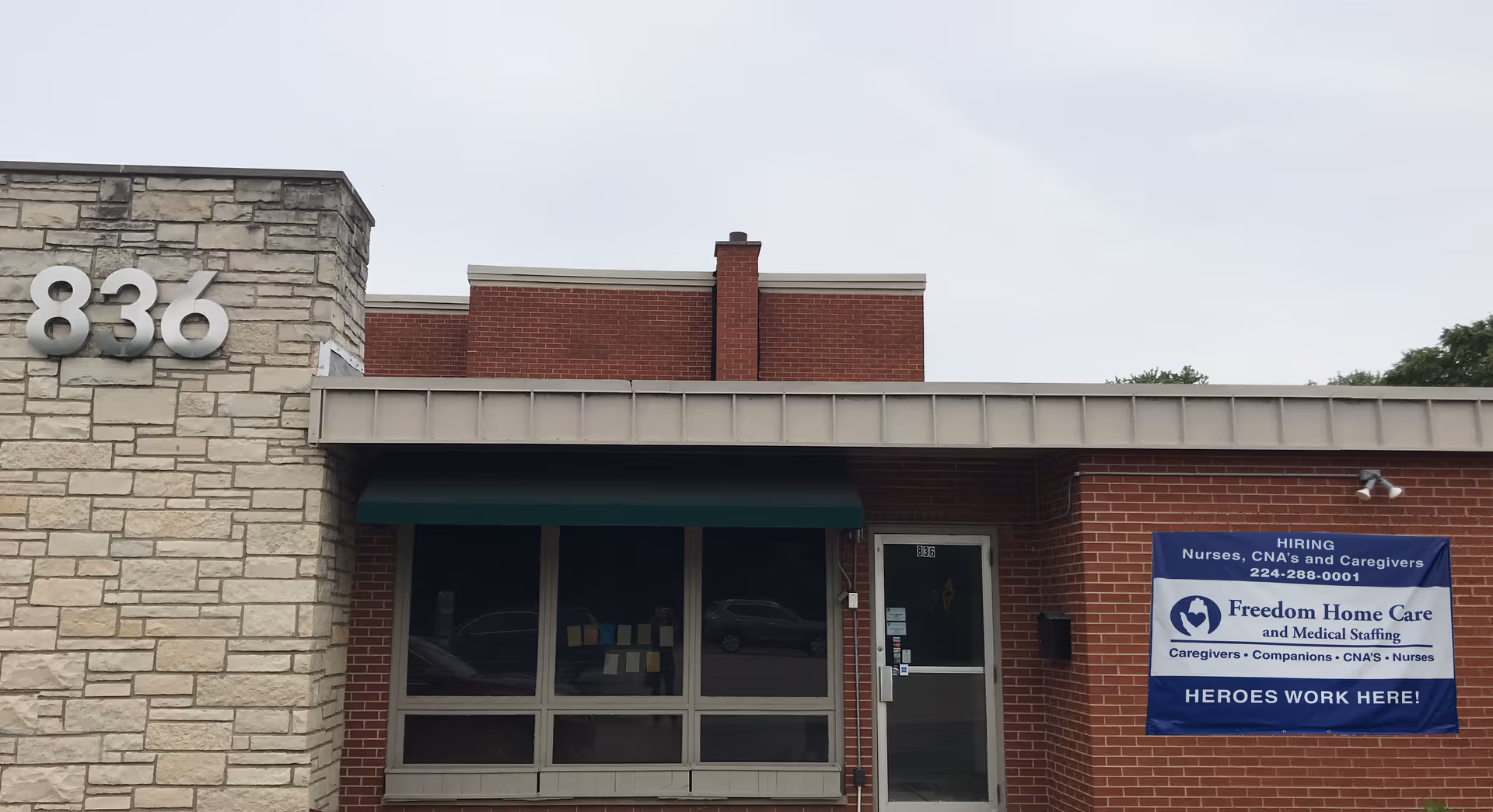 Exterior view of Freedom Home Care building with front entrance and a hiring banner.
