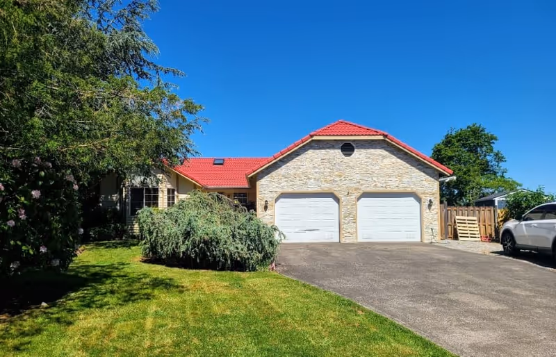 Front view of Caring Arms Adult Family Home, a stone-faced house with a two-car garage.