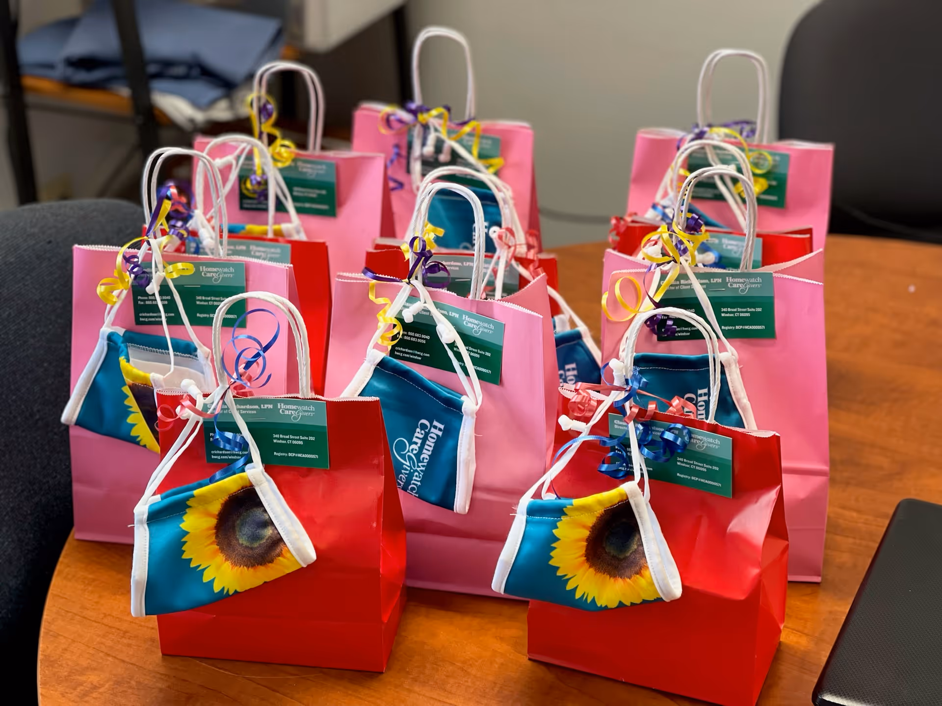 Colorful gift bags with ribbons arranged on a wooden table indoors.