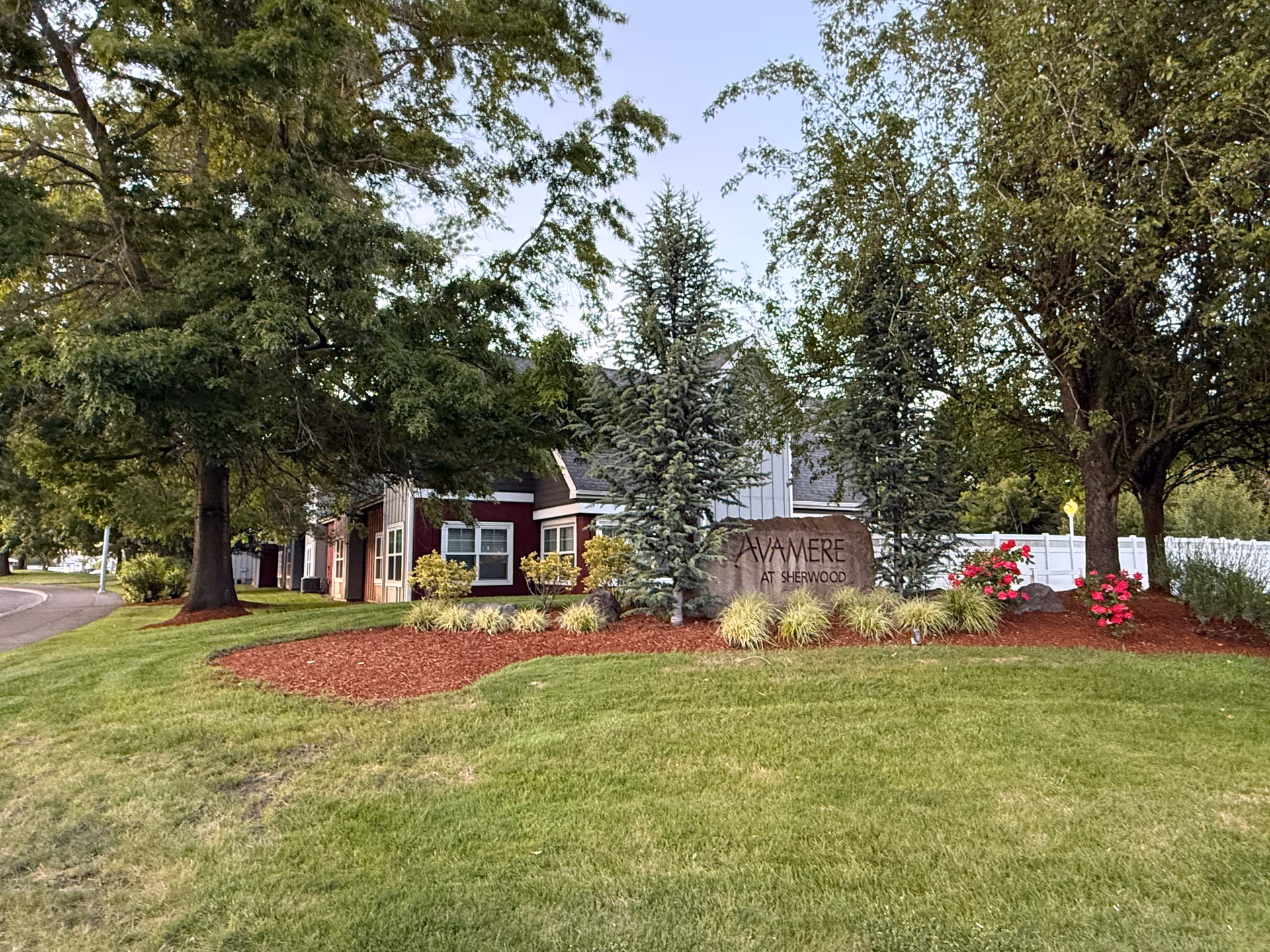 Exterior view of Avamere at Sherwood entrance with landscaped lawn, trees, and sign.