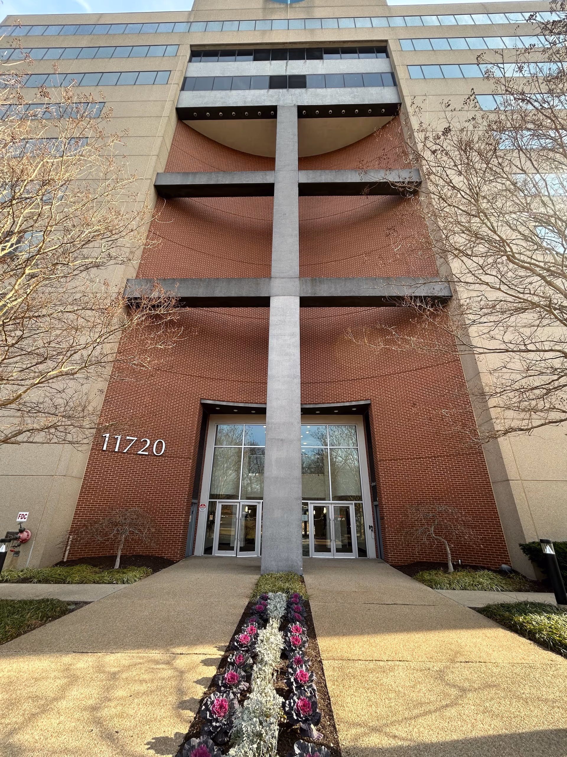 Front entrance of a tall brick building with double doors and a landscaped walkway.
