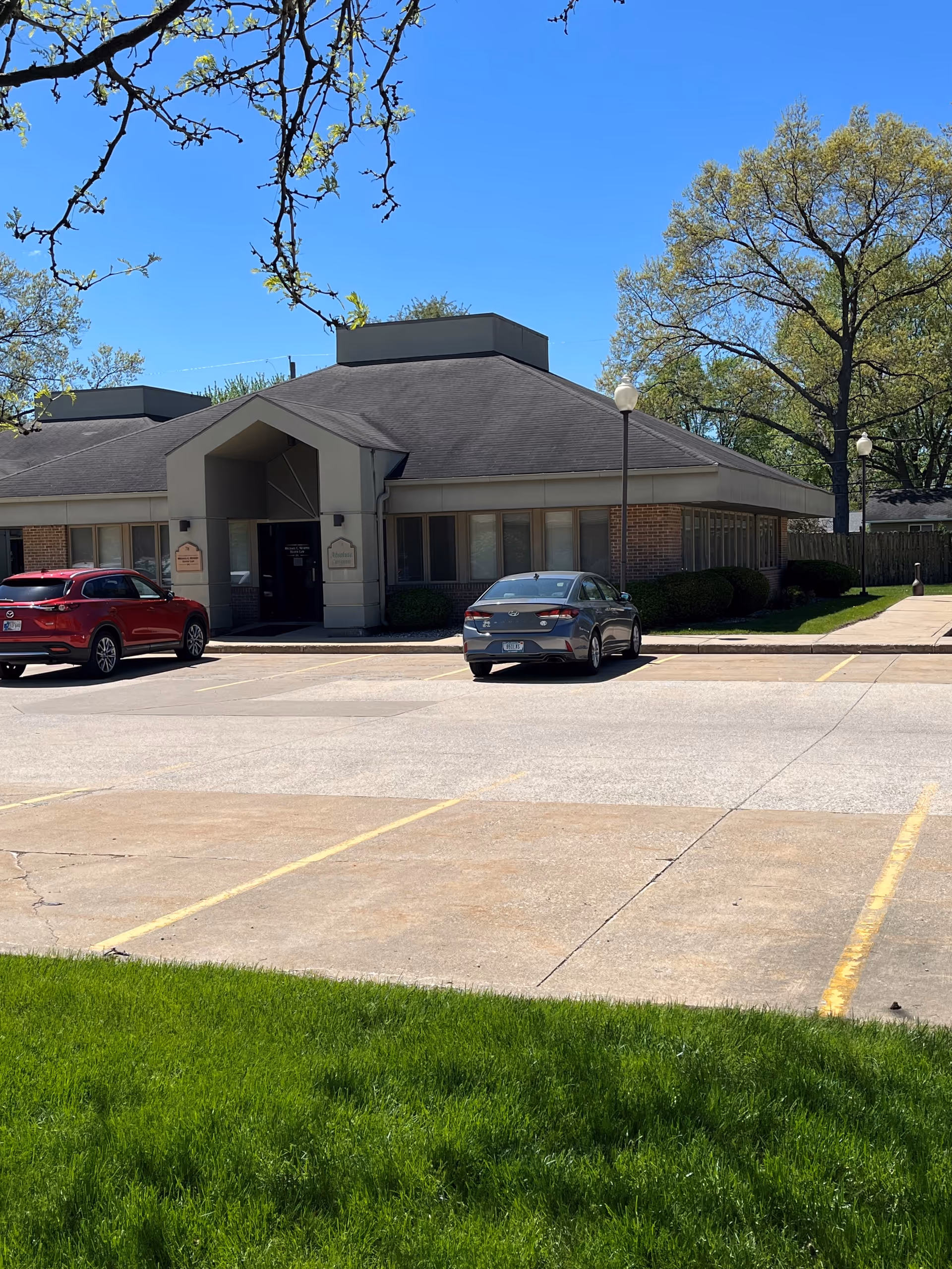 Exterior view of a senior living facility front entrance with two parked cars