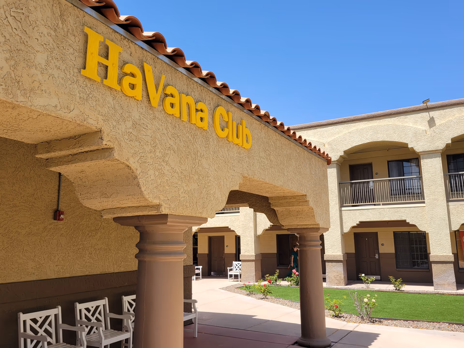 Exterior view of senior living facility entrance with arches, columns, and balconies.