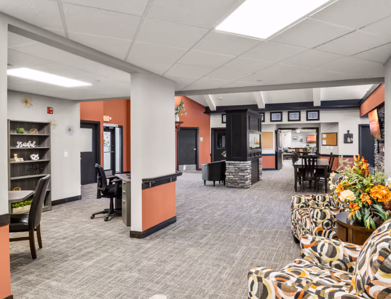 Spacious interior lounge at Maple Grove senior facility with patterned chairs and tables.