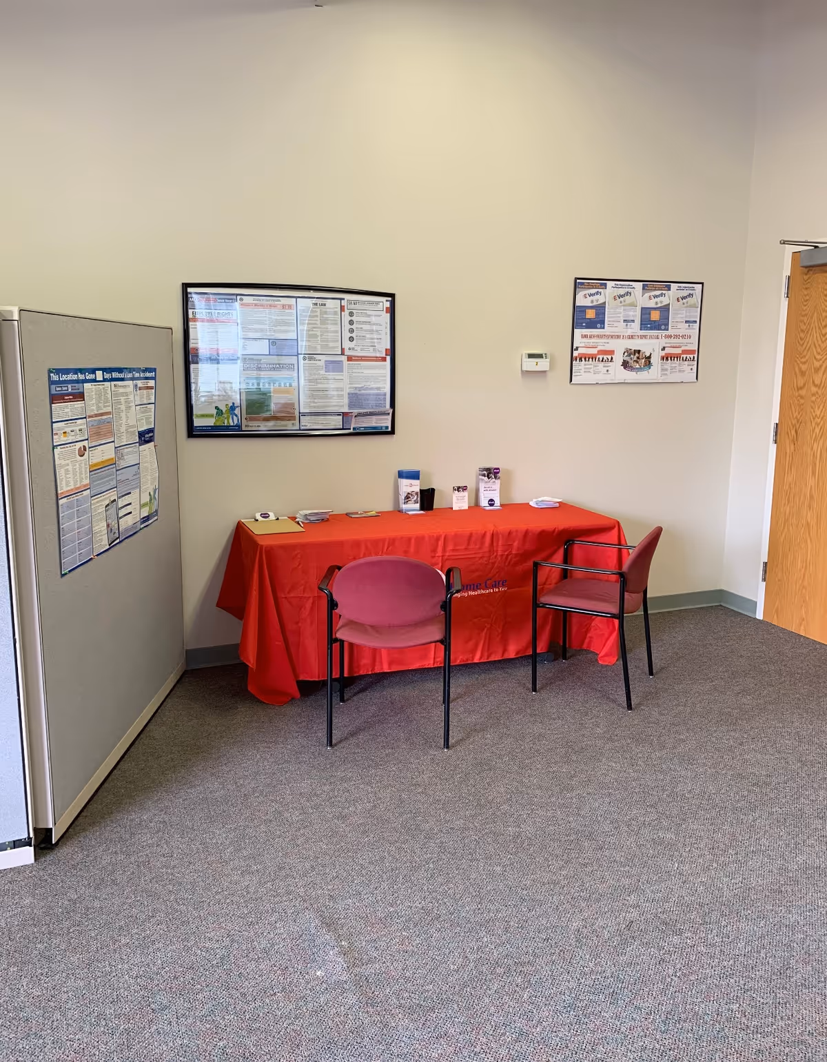 Interior hallway with a red-draped information table and two chairs beside bulletin boards.