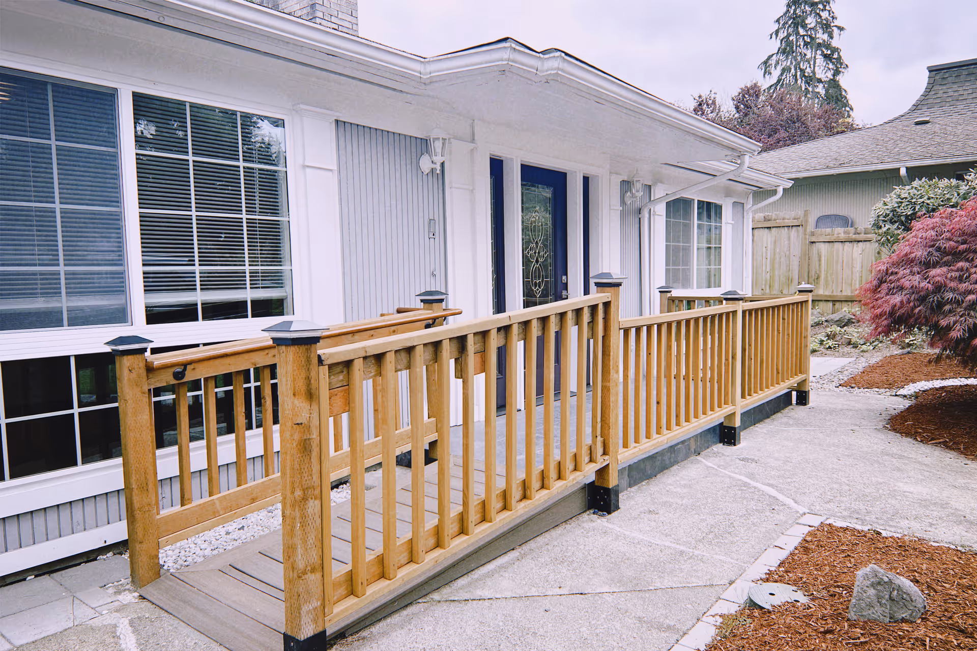 Wooden ramp and railing lead to a white, single-story facility entrance.