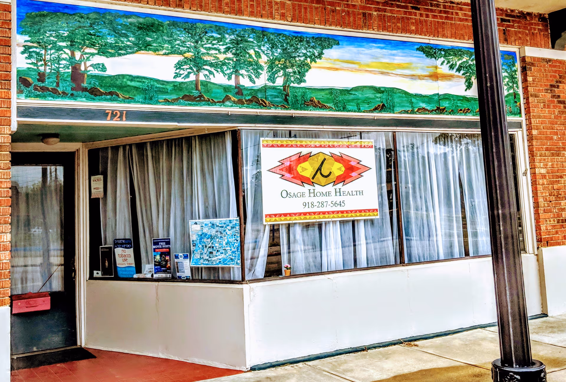 Exterior storefront of Osage Home Health with mural, banners, and curtained windows.