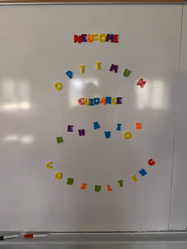 Whiteboard with colorful magnet letters spelling a welcome message in an interior room.