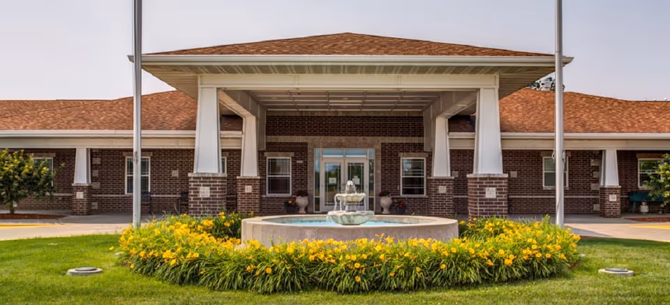 Exterior view of Prairie Hills at Independence entrance with a fountain and yellow flowers