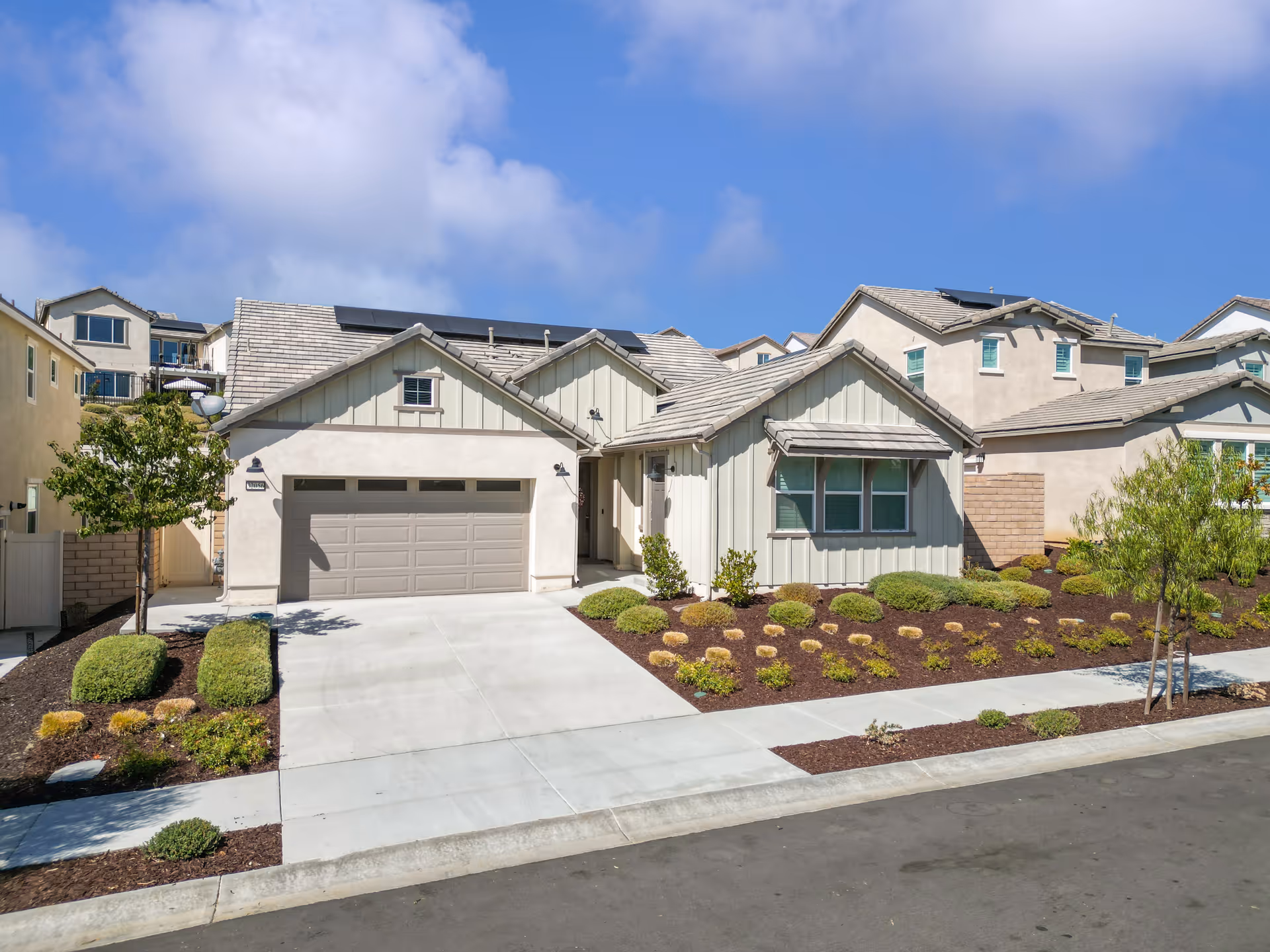 Front view of a beige, single-story senior care facility with a two-car garage and landscaped yard.